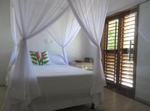 a bedroom with a white canopy bed with a window at Concept House Caraiva in Caraíva