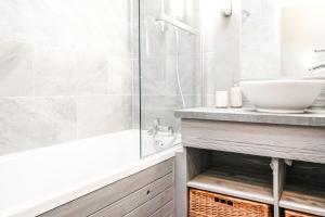 uma casa de banho com uma banheira, um lavatório e um chuveiro em South-facing newly renovated 2-bed apartment Les Terrasses d'Eos em Flaine