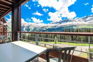a table and chairs on a balcony with a view of mountains at South-facing newly renovated 2-bed apartment Les Terrasses d'Eos in Flaine