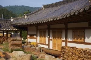 a building with yellow doors and a pile of logs at Korean Traditional House - Chungnokdang in Boseong