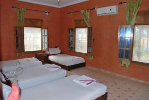 a room with three beds and windows and red walls at Gite Souss in Oulad Teïma