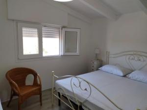 a bedroom with a bed and a chair and two windows at Dimora Arnesano in Torre Lapillo
