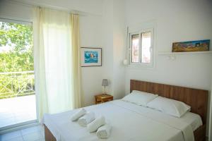 a bedroom with two beds with white sheets and a window at Villa Elena in Vourvourou