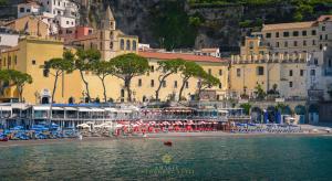 a beach with chairs and umbrellas in front of a city at Amalfi Cathedral Suite in Amalfi
