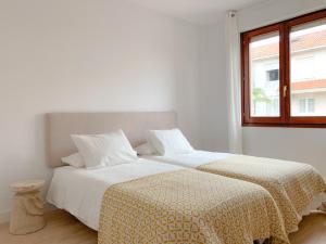 2 camas en una habitación blanca con ventana en ACOGEDOR APARTAMENTO CON TERRAZA Y PARKING Publico EN COMILLAS, en Comillas