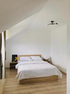 a white bedroom with a large bed with white sheets at Vila Norina in Oeşti-Pămînteni