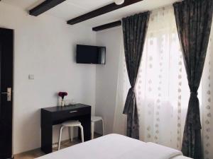 a bedroom with a bed and a desk and a window at Vila Norina in Oeşti-Pămînteni