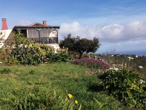 uma casa no topo de uma colina relvada com flores em Casa Rural La Florida em Barlovento