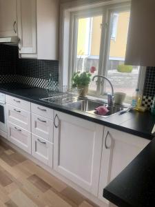 uma cozinha com armários brancos, um lavatório e uma janela em Villa Syren em Söderköping