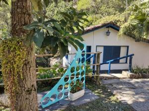 a blue staircase next to a tree in front of a house at Vila da Sol Itaipava casas e estúdios in Itaipava