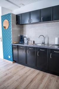 a kitchen with black cabinets and a sink at CUDJOE in Dinan