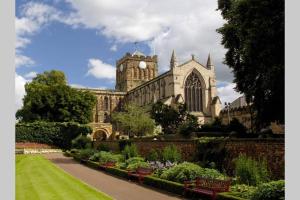 un edificio con torre dell'orologio e giardino di Hexham Town Centre, Market Place View a Hexham