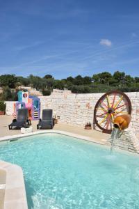 a swimming pool with a waterwheel in a yard at Quei Trulli Divini in Martina Franca