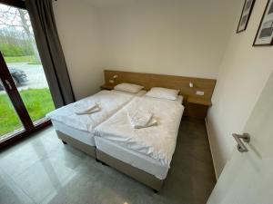 una camera da letto con un letto con lenzuola bianche e una finestra di Resort Nová Pec a Nová Pec