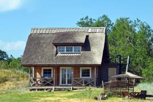 a small house with a gambrel roof on a field at Judbidzi in Pape