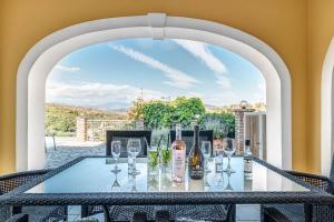 una mesa con copas y botellas de vino en el patio en Agios Stefanos Bay - Villa Dimitris en Ágios Stéfanos
