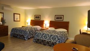 um quarto de hotel com duas camas e uma mesa em Bouctouche Bay Inn em Bouctouche
