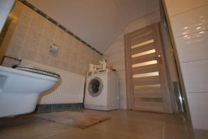 uma casa de banho com uma máquina de lavar roupa ao lado de uma porta em Apartament przy łysej polanie em Tymień