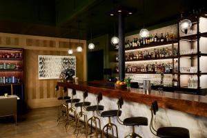 um bar com um monte de bancos num quarto em The Grady Hotel em Louisville