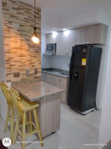 Il comprend une cuisine équipée d'un réfrigérateur noir et d'un comptoir. dans l'établissement Hermoso Apartamento Amoblado, à Carthagène des Indes