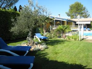 un patio con dos sillas azules y un árbol en Le Zenith, en LʼIsle-sur-la-Sorgue
