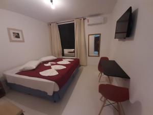 um quarto com uma cama e 2 cadeiras e uma televisão em Suite Real Residencial no Rio de Janeiro