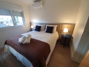 een slaapkamer met een groot bed met twee handdoeken erop bij Temporada Gramado e Canela - Apartamento Centro Campos de Canella in Canela +18 foto's