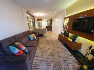 een woonkamer met een bruine bank en een televisie bij Temporada Gramado e Canela - Apartamento Centro Campos de Canella in Canela