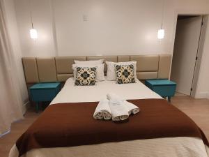 een slaapkamer met een bed met 2 handdoeken en kussens bij Temporada Gramado e Canela - Apartamento Centro Campos de Canella in Canela