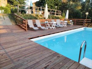 drewniany taras z leżakami i basenem w obiekcie Le Mimose B&B w mieście Vinci