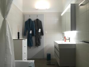 a bathroom with a sink and a robe hanging on a wall at Maison SANS SOUCI in Lajoux +41 photos