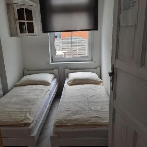 two beds in a small room with a window at Apartamenty Wikoli in Międzyzdroje