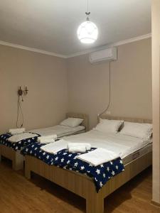 two twin beds in a bedroom with a light at Happy Holiday in Akhaltsikhe