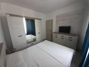 图尔恰Apartament Gabi的卧室里有一张白色的床和一台电视