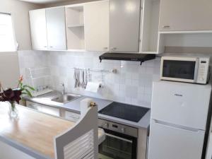 a white kitchen with a sink and a microwave at Agréable F2, jardin, garage, fibre, clim ch in Fort-de-France