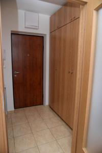un corridoio con porta in legno e pavimento piastrellato di Studio Apartman Lukavica a Sarajevo
