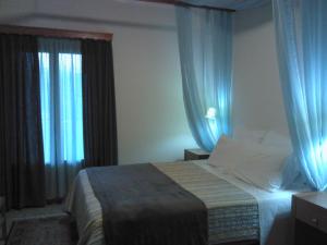 a bedroom with a large bed with blue curtains at Menta( Archontiko Machalioti ) in Karpenision