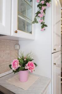 a pink vase filled with pink roses on a kitchen counter at ⭑⭑⭑⭑⭑La perla Rosa nel centro storico a Carloforte in Carloforte