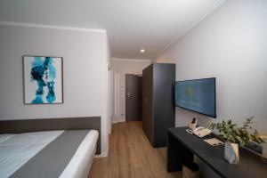 1 dormitorio con 1 cama y TV en la pared en Emily Hotel Leipzig Neue Messe, en Leipzig