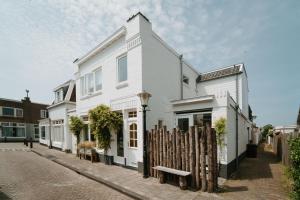 a white house on a street with a wooden fence at Tiny Beach House Zandvoort in Zandvoort
