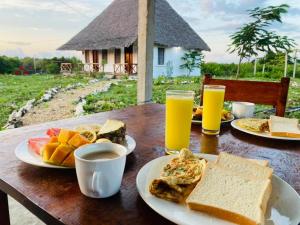 a table with plates of food and drinks on it at Habibis Bottle House in Nungwi