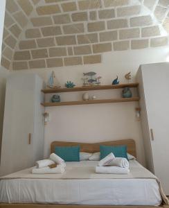 Ce lit se trouve dans une chambre dotée d'un mur en briques. dans l'établissement casa venere 27 Favignana, à Favignana