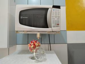 un four micro-ondes et un vase de fleurs sur un comptoir de cuisine dans l'établissement Studio 137 ao Lado Metrô Internet 300MG, à São Paulo