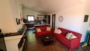 a living room with two red couches and a kitchen at Terrazze al Mare (Urlaub an Sardiniens Westküste) in Torre Dei Corsari