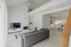 a living room with a gray couch and a tv at 20 da Vila - Apartment With Mezzanine With Panoramic Terrace in São Bartolomeu de Messines