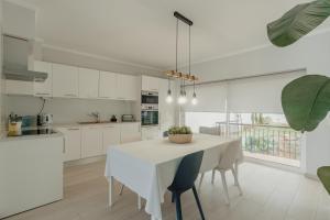 a white kitchen with a white table and chairs at 20 da Vila - Apartment With Mezzanine With Panoramic Terrace in São Bartolomeu de Messines