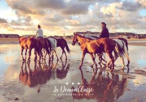a group of people riding horses on the beach at La Deauvillaise - Résidence du Golf in Deauville