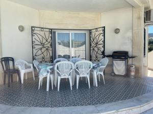 un grupo de sillas blancas, una mesa y una parrilla en Luxury Villa with private pool near Ronda, en Arriate