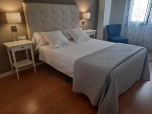 a bedroom with a large white bed and a blue chair at Apartamentos Alameda in Ronda