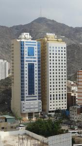 two tall buildings in a city with mountains in the background at فندق الركائز in Makkah